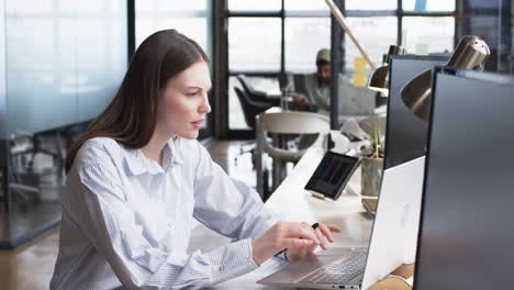 Young-Caucasian-woman-works-intently-at-her-computer-in-business-office