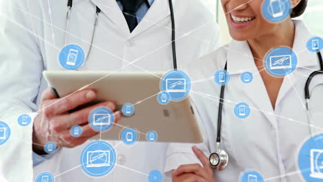 Animation-of-network-of-connections-with-icons-over-diverse-doctors-using-tablet