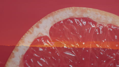 Composition-of-halved-grapefruit-and-sunset-on-red-background