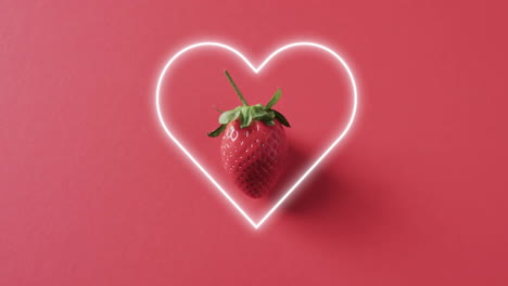 Composition-of-neon-heart-and-strawberry-on-pink-background