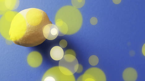 Composition-of-lemon-and-spots-of-light-over-blue-background