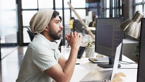 Young-Asian-man-in-a-business-office-setting,-focused-on-his-computer-screen