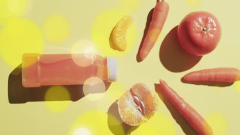 Komposition-Aus-Lichtpunkten-über-Einer-Flasche-Fruchtsaft,-Karotten-Und-Orangen-Auf-Gelbem-Hintergrund