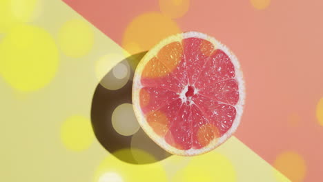 Composition-of-halved-grapefruit-and-yellow-spots-on-yellow-and-red-background