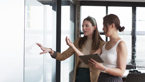 Young-Caucasian-woman-and-Asian-woman-discuss-business-chart-in-an-office
