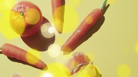 Komposition-Aus-Gelben-Lichtflecken-über-Mandarine-Und-Karotten-Auf-Gelbem-Hintergrund