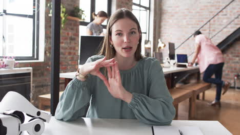 Young-Caucasian-woman-looks-surprised-at-her-desk-in-a-modern-business-office-on-video-call