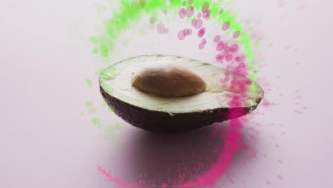 Composition-of-spots-of-light-over-halved-avocado-on-pink-background