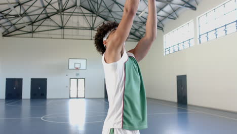 Young-biracial-man-practices-basketball-in-an-indoor-court