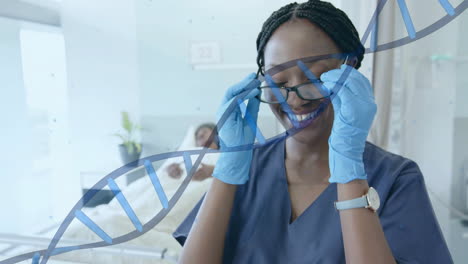 Animation-of-dna-strand-over-happy-african-female-doctor-removing-glasses-in-hospital-ward