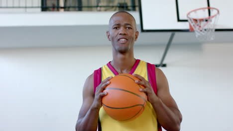African-American-man-holds-a-basketball-in-a-gym