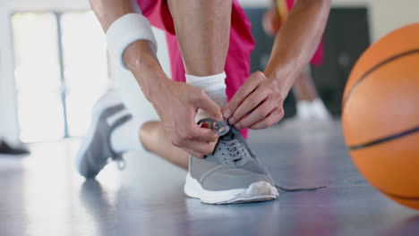 Athlete-tying-shoelaces-in-an-indoor-court
