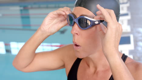 Caucasian-female-swimmer-athlete-adjusts-her-swimming-goggles