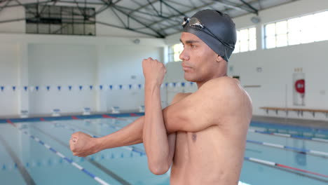 Young-biracial-male-athlete-swimmer-stretches-before-swimming