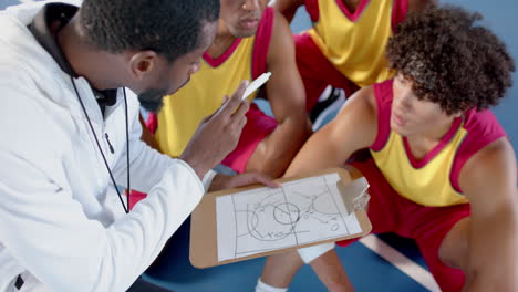 Afroamerikanischer-Trainer-Bespricht-Strategie-Mit-Jungen-Spielern-In-Einer-Sportanlage