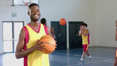 Junger-Afroamerikanischer-Mann-Hält-Einen-Basketball-In-Einem-Fitnessstudio,-Mit-Kopierraum