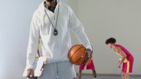 Afroamerikanischer-Trainer-Hält-Einen-Basketball-In-Einer-Turnhalle