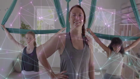 Animation-of-glowing-network-over-diverse-female-instructor-and-teenage-girls-practicing-aerial-yoga