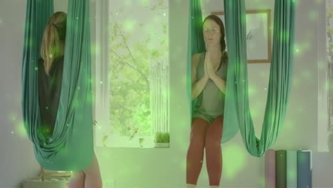 Animation-of-green-lights-over-caucasian-female-aerial-yoga-instructor-and-teenage-girl-meditating