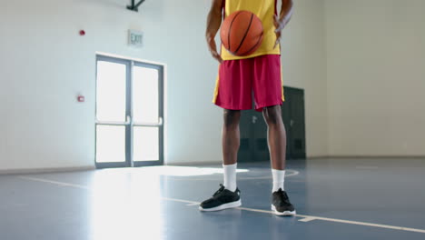 Young-African-American-man-holds-a-basketball-in-a-gym