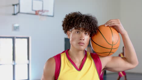 Young-biracial-man-poses-in-a-basketball-court