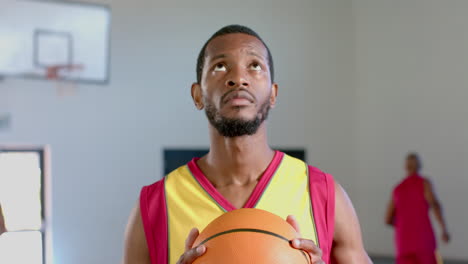 African-American-man-holds-a-basketball-in-a-gym
