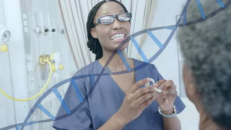 Animation-of-dna-strand-over-african-american-female-doctor-fitting-hearing-aid-for-senior-patient
