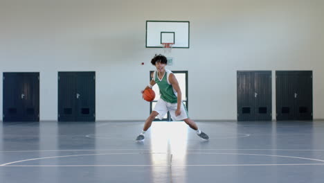 Young-biracial-man-plays-basketball-in-an-indoor-court