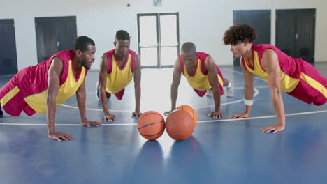 Diverse-basketball-players-perform-push-ups-in-a-gym