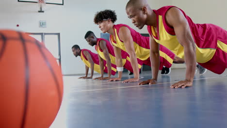Diverse-basketball-players-perform-push-ups-in-a-gym