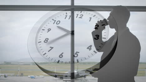 Animation-of-clock-with-fast-moving-hands-over-caucasian-businessman-using-smartphone-at-airport