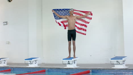Young-biracial-male-athlete-swimmer-stands-proudly-with-an-American-flag