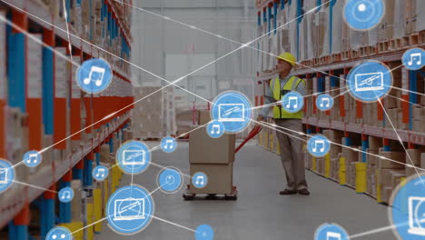 Animation-of-network-of-media-icons-over-caucasian-male-worker-moving-trolley-at-warehouse