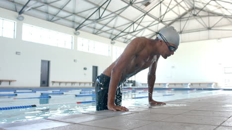 Young-biracial-male-athlete-swimmer-at-the-poolside,-ready-for-a-swim