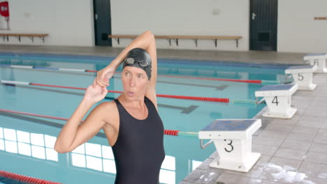 Caucasian-female-swimmer-athlete-adjusts-her-swimming-cap-poolside