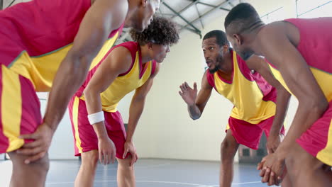 Jugadores-De-Baloncesto-Afroamericanos-Se-Apiñan-En-Un-Gimnasio,-Discutiendo-Estrategia