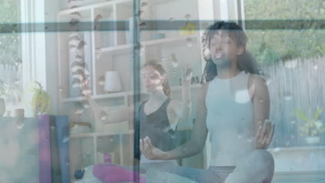 Animation-of-water-droplets-on-window-over-happy-diverse-teenage-girls-practicing-yoga-meditation