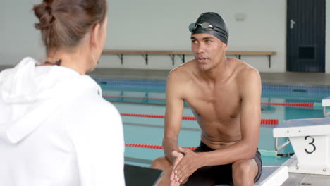 Swimmer-discussing-performance-with-coach-poolside