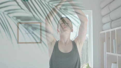 Animation-of-green-palm-leaves-over-caucasian-woman-practicing-yoga-meditation-in-sunny-room