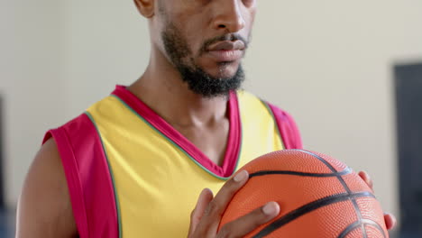 Fokussierter-Afroamerikanischer-Mann,-Der-Drinnen-Einen-Basketball-Hält