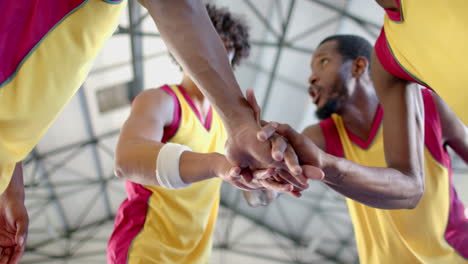 Diverse-basketball-team-huddles,-showing-unity-with-a-group-hand-stack