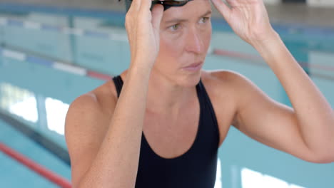 Caucasian-female-swimmer-athlete-adjusts-her-swimming-goggles-at-the-pool