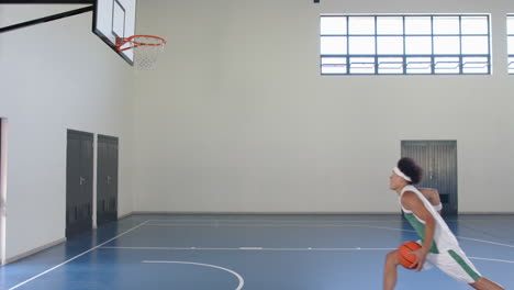 Junger-Mann-Mit-Gemischter-Abstammung-Spielt-Basketball-Im-Innenbereich,-Mit-Kopierraum