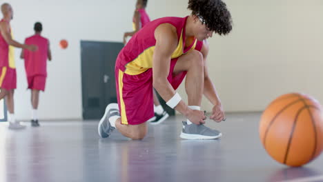 Young-African-American-man-ties-his-shoe-on-the-basketball-court