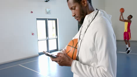 African-American-coach-checks-his-phone-in-a-gym,-with-copy-space