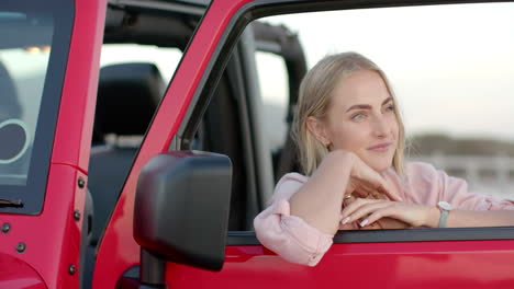 Young-Caucasian-woman-leans-on-a-car-door-on-a-road-trip,-with-copy-space
