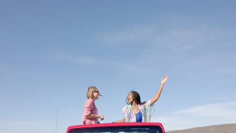 Young-African-American-and-Caucasian-women-enjoy-a-sunny-day-on-a-road-trip-with-copy-space