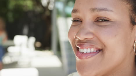 Close-up-of-a-young-biracial-woman-smiling-outdoors-with-copy-space
