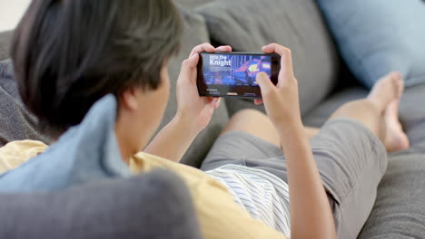 Asiatischer-Teenager-Spielt-Zu-Hause-Ein-Spiel-Auf-Seinem-Smartphone