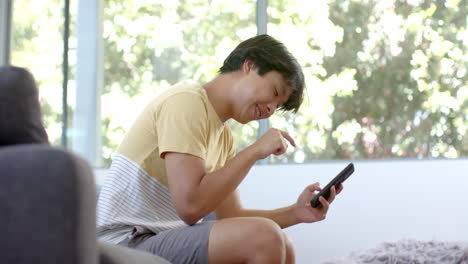 Teenage-Asian-boy-enjoys-a-game-on-his-phone-at-home